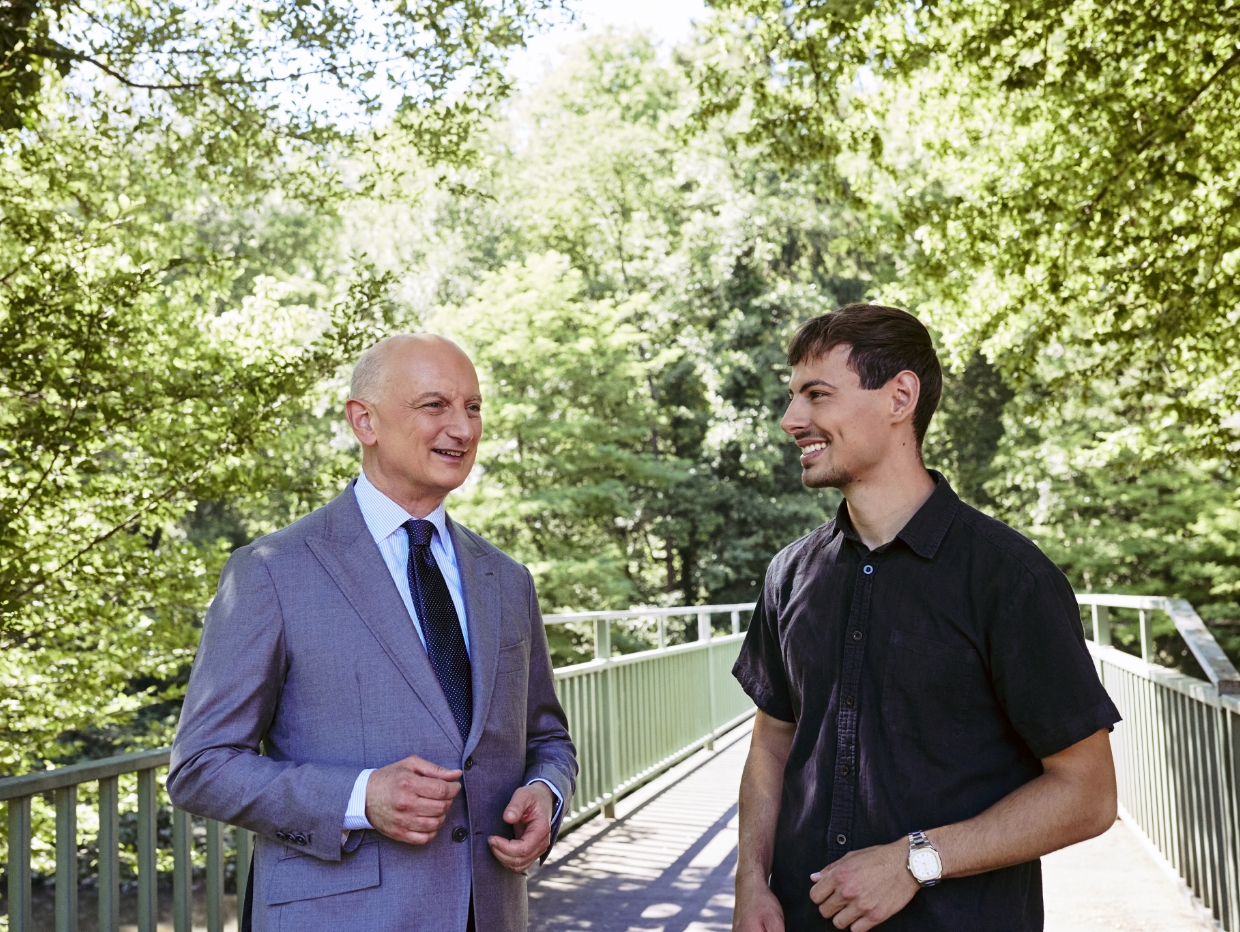 Dr. Nikolas Stihl und Tamino Soubawi stehen auf einer Br&uuml;cke umgeben von B&auml;umen.