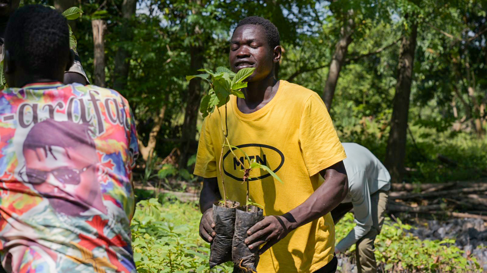 Ein Mann mit Setzlingen in den H&auml;nden bei einer Pflanzaktion in Uganda.